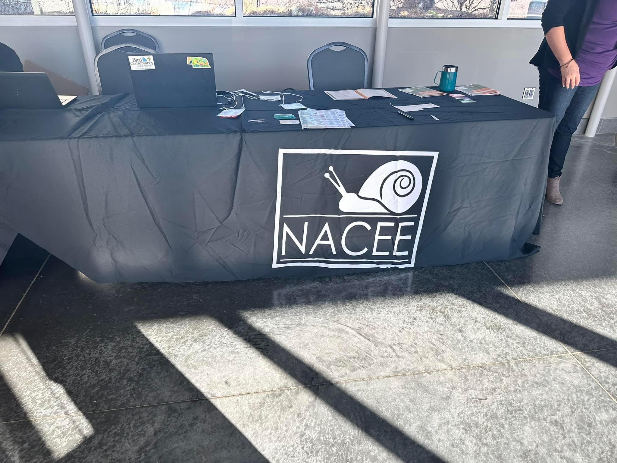 a table with a cover of a company called "NACEE" which features a drawing of a snail on top of the words - jacqelle lane